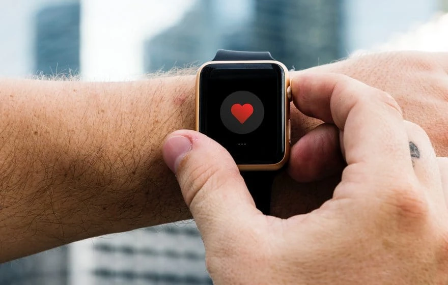 A person interacts with a smartwatch displaying a red heart icon on the screen, highlighting advanced health technology for effective health or fitness tracking.