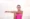 A woman in a pink vest top stretches her arm across her chest outdoors, looking towards the camera—embracing wellbeing much like exploring the 7 Major Benefits of NAD+ IV Therapy.