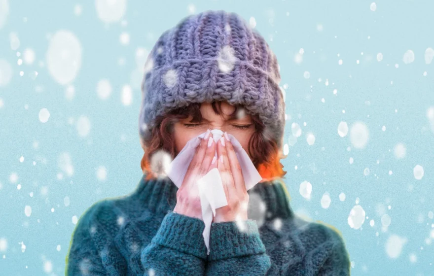 woman sneezing into tissue in winter snow