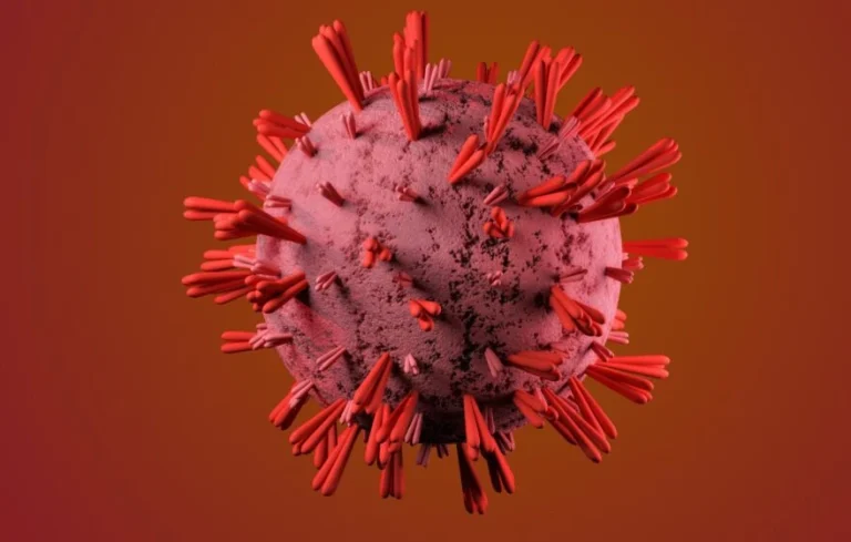 A 3D rendering of a spherical virus particle with protruding red spike proteins against a reddish gradient background, evoking the pale tones often seen in anaemic lips—one of the subtle signs of anaemia.