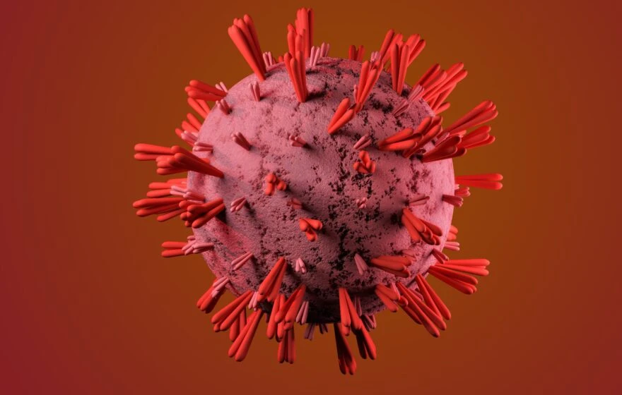 A 3D rendering of a spherical virus particle with protruding red spike proteins against a reddish gradient background, evoking the pale tones often seen in anaemic lips—one of the subtle signs of anaemia.