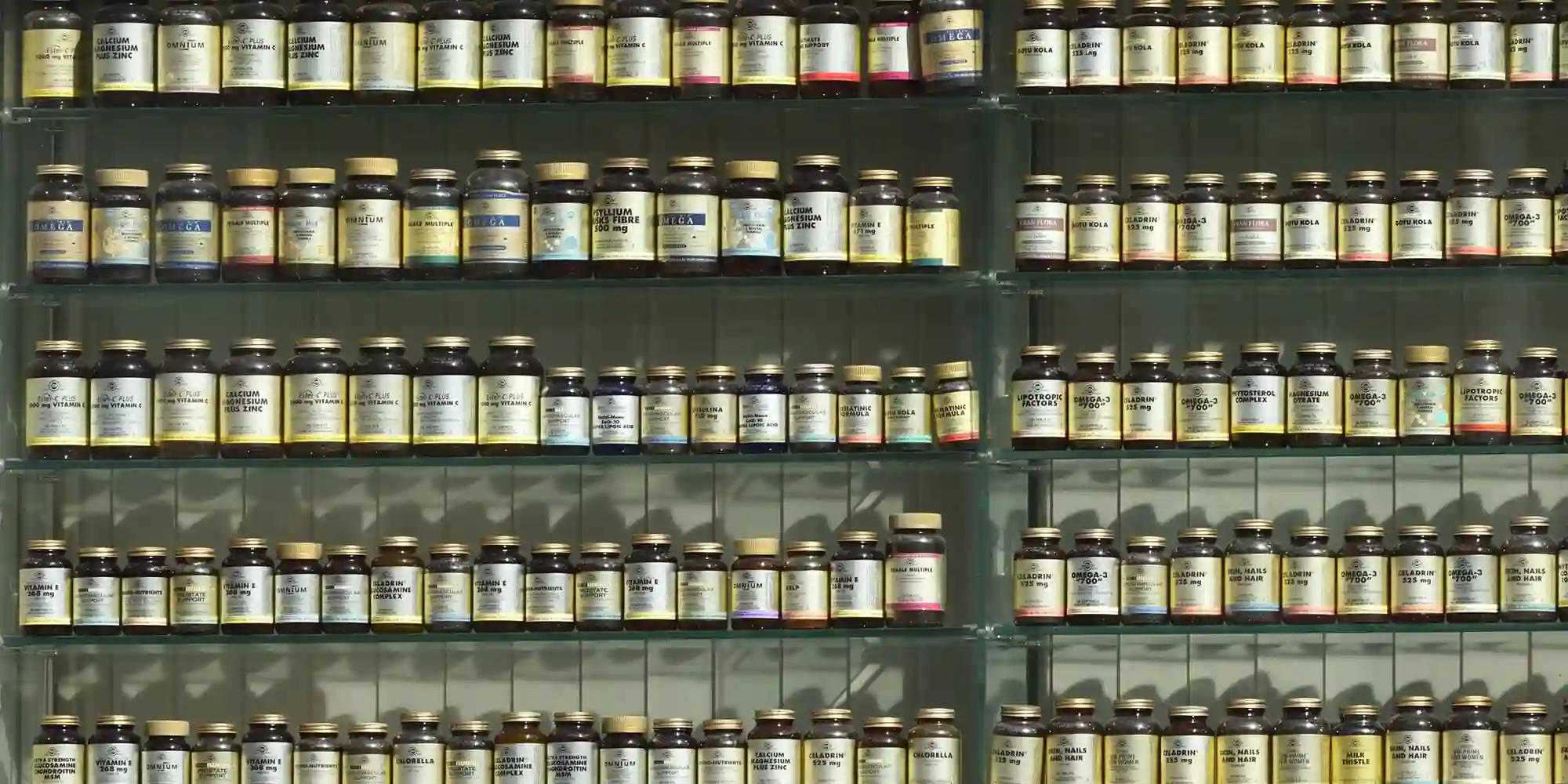 Shelves filled with rows of glass bottles, each labelled with text listing the 7 essential vitamins for boosting your immune system, organised neatly in a well-lit display.