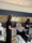 A woman sits in a medical chair receiving a drip while two staff members in black uniforms and gloves attend to her, highlighting the clinic's expert services.
