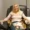 A woman sits in a recliner receiving IV therapy, holding a cup in one hand with magazines on her lap.