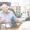 An older man in a blue shirt sits at a desk, discussing the Attomarker COVID Antibody Test with another person whose back is to the camera in an office setting.