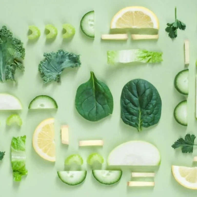 An assortment of sliced and whole green vegetables and lemon—among the best anti-inflammatory foods—arranged neatly on a light green background.