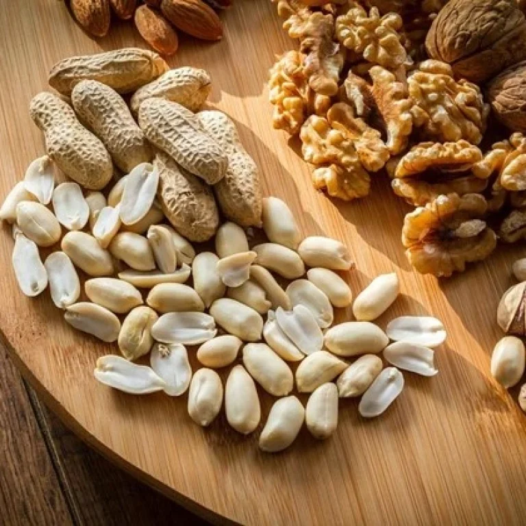 A wooden board with unshelled and shelled peanuts, walnuts, pistachios, and almonds on a wooden surface—these nuts are not only delicious but also packed with health benefits, including essential amino acids such as Ornithine.