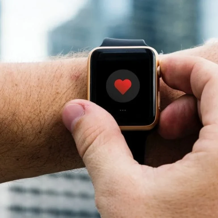A person interacts with a smartwatch displaying a red heart icon on the screen, highlighting advanced health technology for effective health or fitness tracking.