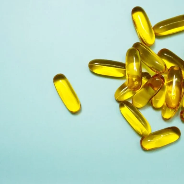 A group of yellow, translucent gel capsules—possibly arginine supplements—scattered on a light blue surface.